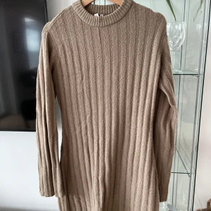 Beige ribbstickad långärmad klänning - Säljer en beige ribbstickad klänning med lång ärm och rund halsringning. Klänningen har en rak passform och är perfekt för kyligare dagar. Enkel och stilren design som passar till många tillfällen.