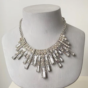 Glittrigt statement-halsband med stora kristaller - Säljer ett maffigt halsband i silverfärg med stora, rektangulära och runda glittriga stenar. Kedjan är grov och justerbar baktill. Perfekt för att lyfta vilken outfit som helst med extra bling och wow-känsla.