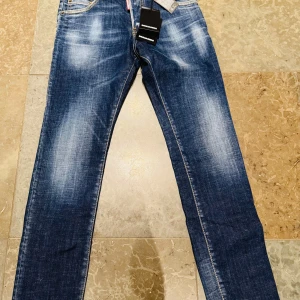 Blå jeansbyxor från Dsquared2 - Hej! Säljer ett par snygga blå oanvända jeansbyxor från Dsquared2  med klassisk femficksdesign och tydliga slitningar. Allt tillhör med köpet, extraknappar.  Märkets logga  syns både fram och bak. Nypris på dessa var 30000 kr. Vid frågor och funderingar är det bara att skriva!👖👖👖