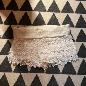 Vita spets-shorts  - Superfina vita shorts med bred resår i midjan och detaljerad spets över hela plagget. Kanten nertill har dekorativa fransar och mönstrad spets.  Perfekta för varma dagar! Står ingen storlek men skullr säga S/M💗