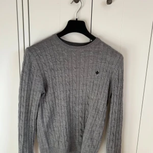 Morris tröja - Säljer en klassisk grå kabelstickad tröja från Morris i 100% merinoull. Tröjan har rund halsringning, lång ärm och diskret logga på bröstet. Perfekt för en stilren och tidlös look.