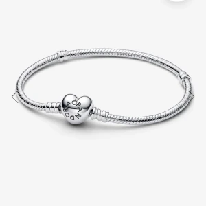 Silver armband från Pandora  - Kan sälja för mycket mindre om man köper fort eftersom jag behöver få sålt den!!! Säljer ett silver armband från Pandora med ett hjärtformat lås där det står 'Pandora' (NYTT SKICK) köpte förra månaden för 799. Säljer för att den är för stor och vill köpa en mindre storlek. Strl 19cm. Kan sälja för mycket mindre om man köper fort eftersom jag behöver få sålt den!!!