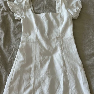 Vit kortklänning med puffärmar och snörning i ryggen - Superfin vit klänning med fyrkantig ringning, puffärmar och snörning i ryggen perfekt till studenten. Jag har inte använt den någon gång men den är köp second hand så kan vara använd tidigare.❤️‍🔥 