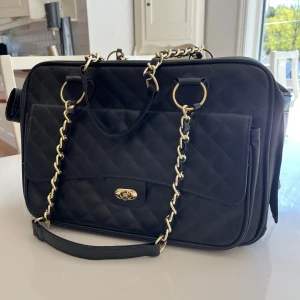 HundväskA Flamingo  - Nästan ny transport väska för den lilla hunden Max 5kg! 40x22x28 Gigi från Flamingo, kostar ny 820kr. Snygg svart axelväska med quiltat mönster och guldfärgade kedjedetaljer på axelremmen. Väskan har flera fack, dragkedja upptill och ett mjukt vitt innerfoder. 