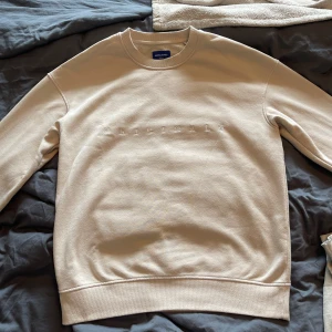 Beige sweatshirt från Jack & Jones - Säljer en stilren beige sweatshirt från Jack & Jones Originals. Lite mer åt oversized hållet, men är otroligt bekväm. Materialet är bomull, den är i storlek L och rekommenderas till dig mellan 180-195. Perfekt för lite varmare dagar då den inte är så tjock utan är otroligt bekväm. Aldrig använt tidigare då jag fick den i födelsedagspresent men kunde inte lämna tillbaka. Nypris 450, mitt pris 149! Hör av dig vid minsta fundering!