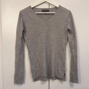 Grå v-ringad tröja från Primark - En enkel och stilren grå v-ringad tröja från Primark. Tröjan har lång ärm och är tillverkad i ett mjukt, tunt stickat material. Storlek 32 men passar Xs.