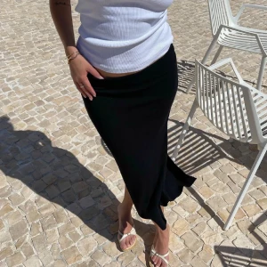 Svart långkjol från Djerf Avenue - Svart långkjol från Djerf Avenue med slits där bak. Kjolen har en rak och stilren passform som sitter snyggt i midjan. Nypris 1100 kr. Ej använd, lappar sitter kvar finns även påse och allt tillbehör. Strlk xxs.