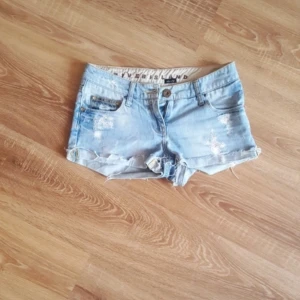 Vintage lågmidjade river island shorts  - Snygga ljusblå jeansshorts från River Island med slitna detaljer och fransig kant. Klassisk femficksmodell med knapp och dragkedja framtill. Perfekta för varma dagar och enkel att matcha med olika toppar.