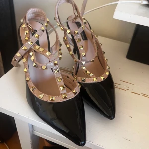 Svarta lackpumps med nitar - Säljer ett par svarta lackpumps med beige remmar dekorerade med guldiga nitar. 