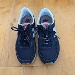 Mörkblå sneakers från New Balance - Skor från New Balance. Storlek 36. Använda  i använt skick. Har blivit lite nopprigt i hälen. Hela. Små defekter (se bild) men inget som stör användningen eller funktionen, inte trasiga. Finns fler bilder!