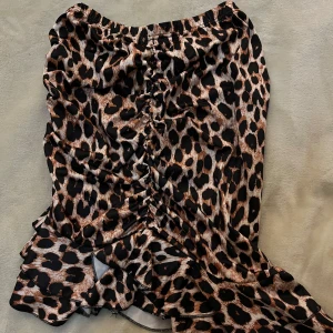 Leopardmönstrad volangkjol - Säljer en snygg leopardmönstrad kjol med volangdetaljer och rynk framtill. Kjolen har elastisk midja och är i en kort modell. Perfekt för dig som vill sticka ut med ett djurmönster.