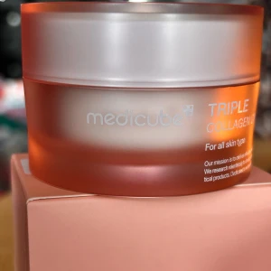 Medicube Triple collagen cream! - Medicube Triple collagen cream. 50 ml. Plomberad.  Medicube Triple Collagen Cream 4.0 är en avancerad anti-aging-kräm som kombinerar tre typer av kollagen för att stärka hudens elasticitet och ge en ungdomligare lyster. Denna kräm är berikad med hydrolyserat elastin från Frankrike, vilket hjälper till att förbättra hudens fasthet och minimera rynkor. Niacinamid, en potent ingrediens för hudens jämnhet, bekämpar pigmentering och ger en klarare hudton, medan adenosin främjar hudens elasticitet.