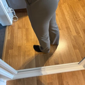 Beiga kostymbyxor med normal passform - Snygga gråa kostymbyxor med hög midja och raka ben. Byxorna har pressveck och stängs med dragkedja och knapp framtill. Perfekta att matcha med många olika färger. Liten mörk fläck på vänster lår men annars som oanvända. Midjemått: 72 cm Innerbenslängd: 74 cm! 💞 Jag är 1,58 m lång och de passar mig bra i längden! Pris går att diskutera! 💞