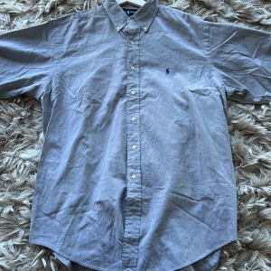 Ralph lauren skjorta - Snygg och stilig Ralph lauren skjorta med lila logga perfekt inför sommaren!                                                   - Fraktas inom 24h!                                                           - Nypris 1500kr mitt pris 349kr                                       
