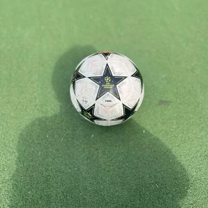 Fotboll Champions leauge - Bilderna visar en fotboll med UEFA Champions League-design, storlek 4. Det är en replica matchboll, perfekt för dig som älskar att spela fotboll med vänner på planen. Bollen har en cool stjärndesign och är använd men i bra skick. Passar både träning och spontana matcher.