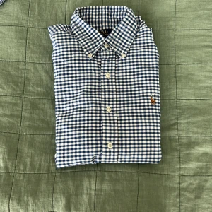 Blårutig skjorta Polo Ralph Lauren S - Klassisk blårutig skjorta från Polo Ralph Lauren i slim fit. Skjortan har vit-blå rutigt mönster, knappar framtill och button down-krage. Broderad logga på bröstet. Perfekt för dig som gillar stilren och tidlös look.
