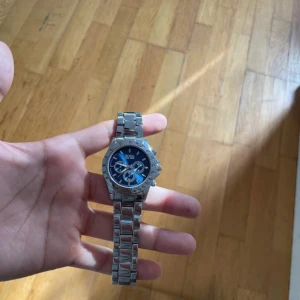 Blå och silverfärgad BOSS klocka - Snygg klocka från BOSS med blå urtavla och silverfärgat armband i rostfritt stål. Klockan har tre mindre urtavlor, tydliga siffror och sportig design. Perfekt accessoar för dig som vill sticka ut med stilren och modern look.