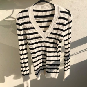 Randig ribbad v-ringad tröja - Vit och svart ribbad tröja med v-ringning och lång ärm. Snyggt randigt mönster och tajtare passform med stretch i. Den är S men passar M