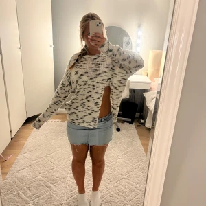 Vit och grå stickad tröja från Zara - Säljer en stickad tröja från Zara i vitt med grått mönster. Tröjan har lång ärm, rund halsringning och en cool slits på sidan som ger en unik look. Perfekt för dig som gillar att sticka ut lite extra.