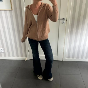 Beige stickad tröja med huva - Säljer denna beigea stickade tröja då jag inte fått användning för den. Den har huva och en dragkedja framtill. Passformen är något oversized. Nyskick! Skriv vid frågor/fler bilder!🥰