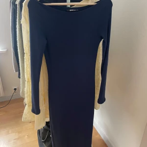 Mörkblå långklänning från Gina Tricot - Snygg mörkblå långklänning från Gina Tricot med lång ärm, den är lite off shoulder. Använd få gånger och är som ny.