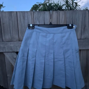 Ljusblå plisserad kortkjol - Snygg ljusblå plisserad kortkjol med klassisk A-linjeform. Kjolen har bred linning och tydliga veck som ger en cool och preppy vibe. Perfekt att matcha med en stickad tröja eller crop top för en trendig look. Kjolen är omsydd från storlek 40 -> storlek 36. Priset går att diskutera ☺️🫶