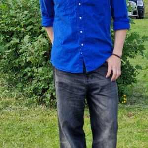 Blå skjorta från Ralph Lauren slim fit - Snygg blå skjorta från Ralph Lauren i slim fit-modell. Skjortan har klassisk krage, långa ärmar och knäppning framtill. Tillverkad i mjuk bomull och passar perfekt för dig som gillar en stilren look med lite färg.