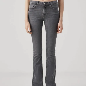 Grå bootcut jeans med hög midja - Snygga grå jeans med bootcut passform och hög midja. Jeansen har klassisk femficksdesign och är tillverkade i stretchigt denimtyg för en bekväm känsla. Perfekta för dig som gillar en tidlös look med lite extra edge.