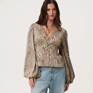 Zebramönstrad blus från Adoore strl 42 - Supersnygg blus från Adoore med zebramönster i beige och brunt. Blusen har v-ringning, knappar framtill och vida, långa ärmar . Endast använd en gång, tyvärr för stor för mig.🥰💕