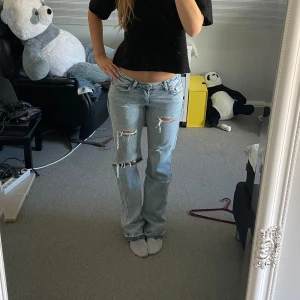 Ljusblå lågmidjade jeans med slitningar - Säljer dessa sjukt snygga ljusblå lågmidjade jeansen med slitningar. Innerbenslängden är ca 88 och midjemått är ca 40.