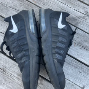 Svarta Nike Air Max sneakers 38.5 - Svarta Nike Air Max sneakers med vit swoosh på sidorna och synlig luftbubbla i sulan. Ovandelen är i mesh och syntet för en sportig look. Klassisk snörning och låg profil gör dem perfekta för en aktiv livsstil, sulan är sliten på hälarna på båda skorna