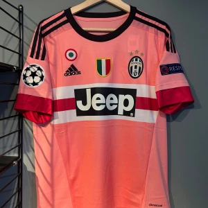 Juventus Pogba rosa matchtröja Adidas - Juventus fotbollströja i rosa med Pogba 10 på ryggen. Tröjan har svarta Adidas-ränder på axlarna, Jeep-logga på bröstet och Champions League-patchar på ärmarna. Tillverkad i lätt och ventilerande climacool-material. Perfekt för dig som älskar fotboll och vill sticka ut. En replika helt ny med tagg!