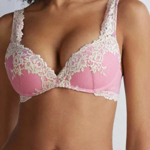 rosa intimissimi bh - Supersöt rosa bh med krämvit blommig spets längs kanterna och axelbanden. Bh:n har vadderade kupor och justerbara axelband för perfekt passform. Materialet är mjukt och stretchigt, vilket gör den både bekväm och snygg.