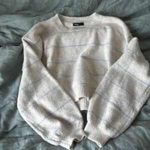 Beige randig stickad tröja Shein - Supermysig stickad tröja från Shein i beige med tunna ljusblå ränder. Tröjan har en loose fit, ribbade muddar och lång ärm. Perfekt för lager-på-lager och chill dagar. Passar dig som gillar en enkel men ändå söt stil.