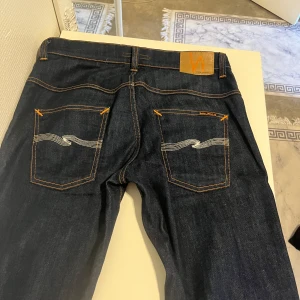 Nudie Jeans - Nudie Jeans – Strl W33 L32 – Nästan nya  Säljer ett par Nudie Jeans i storlek W33 L32. Klassisk modell med mörk tvätt. Använda endast 5–6 gånger och är i mycket gott skick – nästan som nya. Inga fläckar, hål eller slitage.                           Nypris 1400kr 