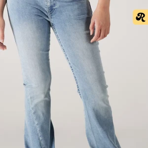 Ljusblå bootcut jeans True Religion - Snygga ljusblå jeans från True Religion med bootcut passform och klassiska kontrastsömmar. Jeansen har stora bakfickor med dekorativa broderier och silverfärgade knappar. Perfekta för dig som gillar en avslappnad men trendig look.