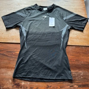 Gymshark Onyx v5 grå / svart - Säljer min Gymshark Onyx v5 i storlek S då den tyvärr var för liten för mig. Tröjan är i super fint skick, inga hål eller defekter lappen finns kvar. Kvittot på bilden finns som äkthetsbevis, skriv till mig ifall du har några frågor.