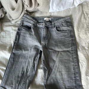 Grå bootcut jeans från Gina Tricot - Snygga grå jeans från Gina Tricot i bootcut-modell. Jeansen har klassisk femficksdesign, normal passform och är tillverkade i mjukt denimtyg. Perfekta för dig som gillar en avslappnad men trendig look.