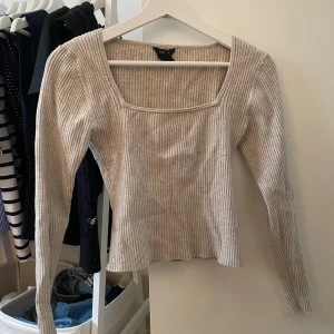 Beige ribbad långärmad tröja Lindex - Superfin beige ribbad tröja från Lindex med fyrkantig urringning och långa ärmar. Sitter snyggt och har en lite tightare passform som framhäver figuren. Perfekt att styla med jeans eller kjol för en clean look.