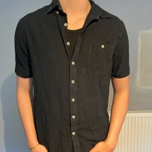 Svart linneskjorta från Dressman - Säljer nu en riktigt stilig kortärmad linneskjorta från Dressman, mycket bra skick och inga defekter. Storlek: L