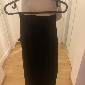 Svart klänning med strassband - Supersnygg svart klänning med raka linjer och tunna axelband i strass som ger en lyxig känsla. Klänningen är ärmlös och har en enkel, elegant design som passar perfekt när du vill sticka ut lite extra.