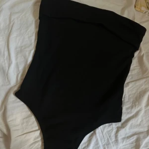 Body - Säljer en svart ribbad body, med ett klister på övre delen så att de sitter på plats & inte faller ner. Samt knappar på nedre delen. 