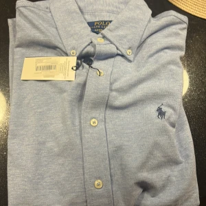 Ljusblå meshskjorta från Polo Ralph Lauren - Snygg ljusblå skjorta från Polo som jag köpte för 1700kr men efter jag köpte den så ändrade jag mig och vill inte ha den mer och fick inte lämna tillbaks den
