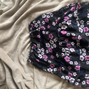 Blommig svart kjol - Svart kjol med blommor. Översta kanterna är uppklippt pågrund av stt de var en klänning innan. Stprlek står inte men gissar på S. Pris kan diskuteras.