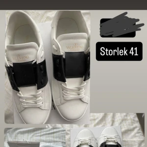 Valentino Garavani Open sneakers vit/svart - Snygga Valentino Garavani Open sneakers i vitt skinn med bred svart läderdetalj över snörningen. Klassisk rund tå och platt sula. Kommer med originalkartong, dustbag och tag. Perfekta för dig som vill ha en clean men lyxig look. Vi kan snacka om priset.