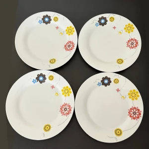 4-pack blommiga tallrikar  - Fina tallrikar med blommigt mönster från Boxxx. Längd: 27 cm Höjd: 3 cm  📌 Något missfärgade på vissa delar (se bild), men i övrigt i fint skick utan sprickor eller nagg.  Passar utmärkt till: 🍽️ Vardagsmiddagar 🍰 Fika och tårta vid kalas 🍽️ Extra tallrikar vid större sällskap eller buffé  Enkla att matcha med annan färgglad servis – både praktiska och dekorativa!