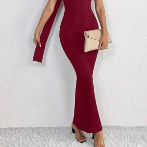 Vinröd långklänning med oneshoulder - Supersnygg vinröd långklänning med figurnära passform och oneshoulder-design. Klänningen har en lång slank siluett, öppen rygg och en cool detalj med bred axelrem. Perfekt för dig som vill sticka ut med en elegant och trendig look. Endast använd 1 gång.