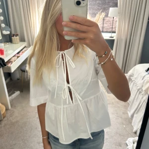 Vit blus med knyt från H&M - Supersöt vit blus från H&M med två knyt framtill och lätt volang nedtill. Använd max 2 gånger !!