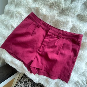 Vinröda högmidjade shorts - Snygga vinröda shorts med klassisk passform. De har hällor för bälte, diskreta fickor och veck framtill som ger en stilren look. Perfekta för sommardagar och lätta att matcha med både crop tops och oversized skjortor.