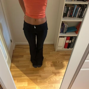 Svarta bootcut byxor låg midja - Säljer ett par svarta byxor/ typ jeans med bootcut och låg midja. Byxorna har två knappar framtill och två fickor och sitter tight upptill med utsvängda ben. 